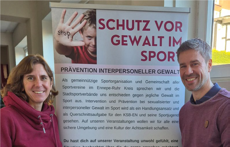Birgit Schmidt und Dr. Marc Hüttebräucker vor dem Banner Schutz vor Gewalt im Sport